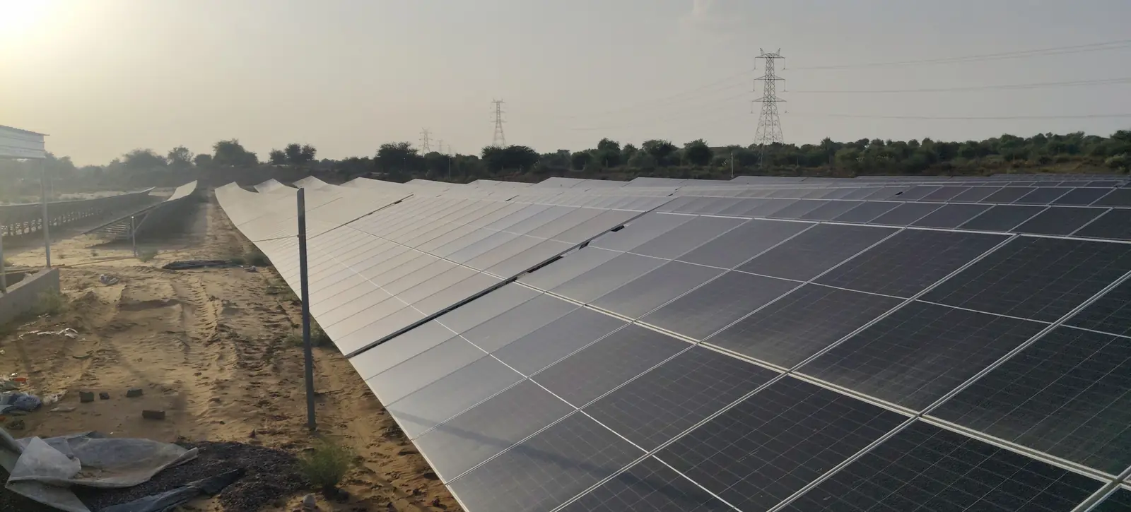 Rows of solar modules with a transmission tower on the horizon