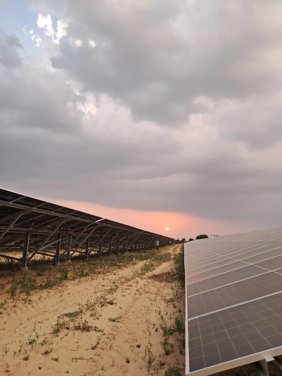 Mounting structure rows beside a sandy access track under an evening sky